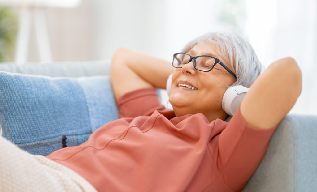 Senior woman listening to music in headphones to reduce stress.